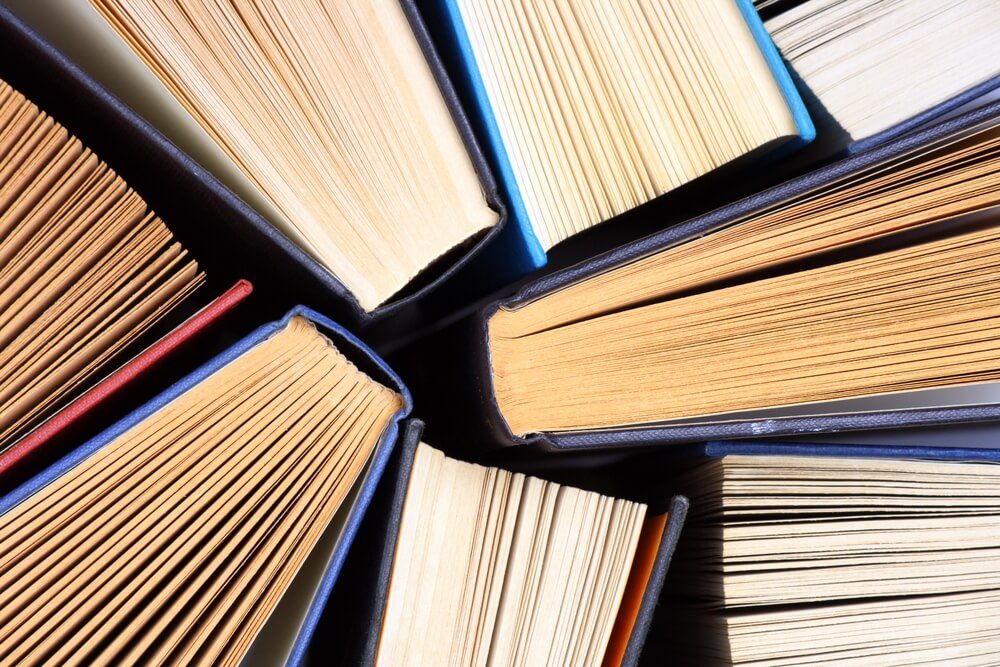 Old and used hardback books or text books seen from above. Books and reading are essential for self improvement, gaining knowledge and success in our careers, business and personal lives 