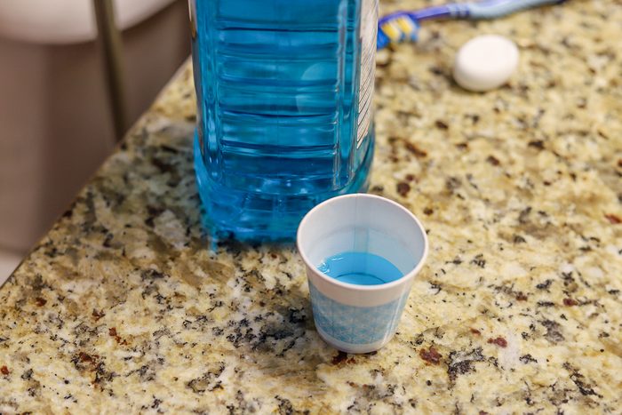 disposable paper cup with mouthwash on bathroom counter