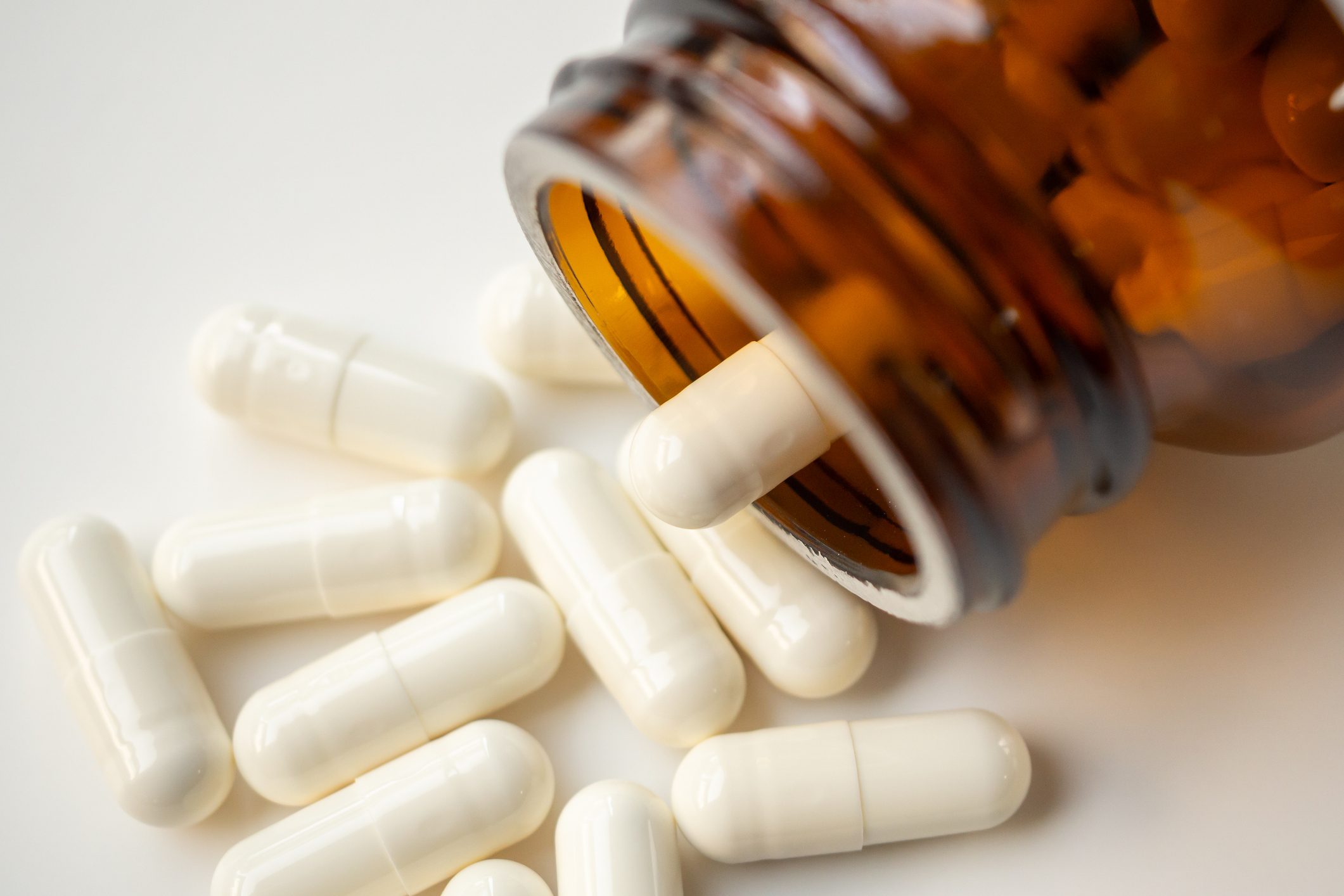 Medicine Pills Capsule Spilling Out Of Bottle On White Background